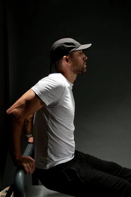 Male member, Alison K., performing a triceps dip on a Pilates reformer machine, demonstrating strength and form in the clean, modern studio environment.